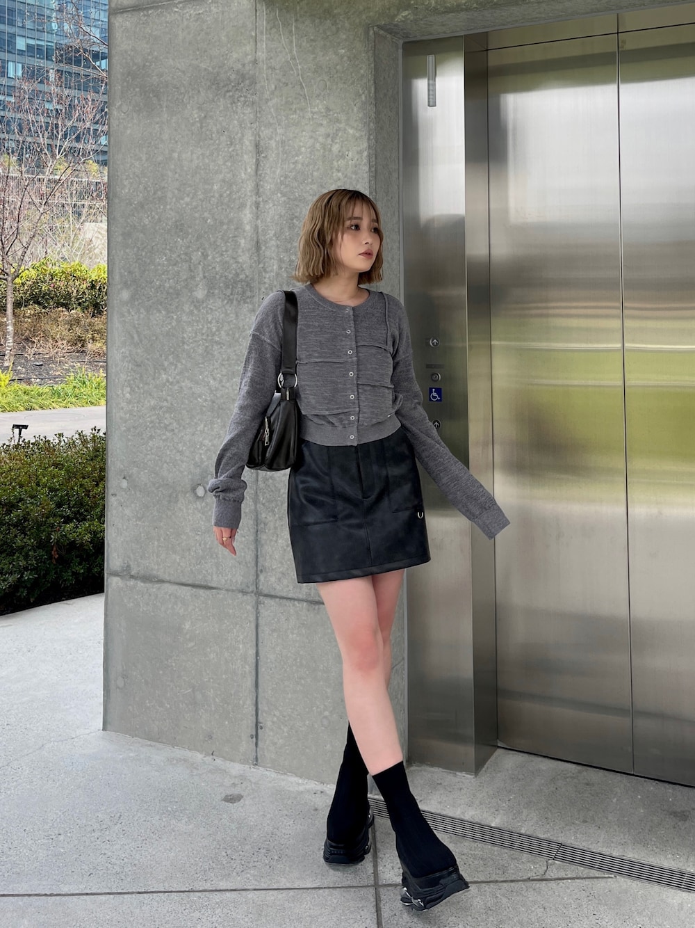 ブラック系のブーツ、ブラック系のスカート、グレー系のカーディガン/ボレロを着用したレディースの春コーディネートの1枚目の写真