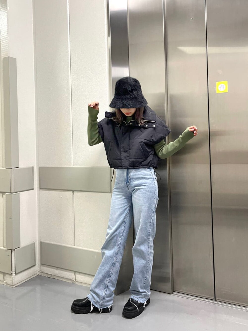 ブラック系のダウンベスト、グリーン系のニット/セーター、ブラック系のハットを着用したレディースの秋コーディネートの1枚目の写真