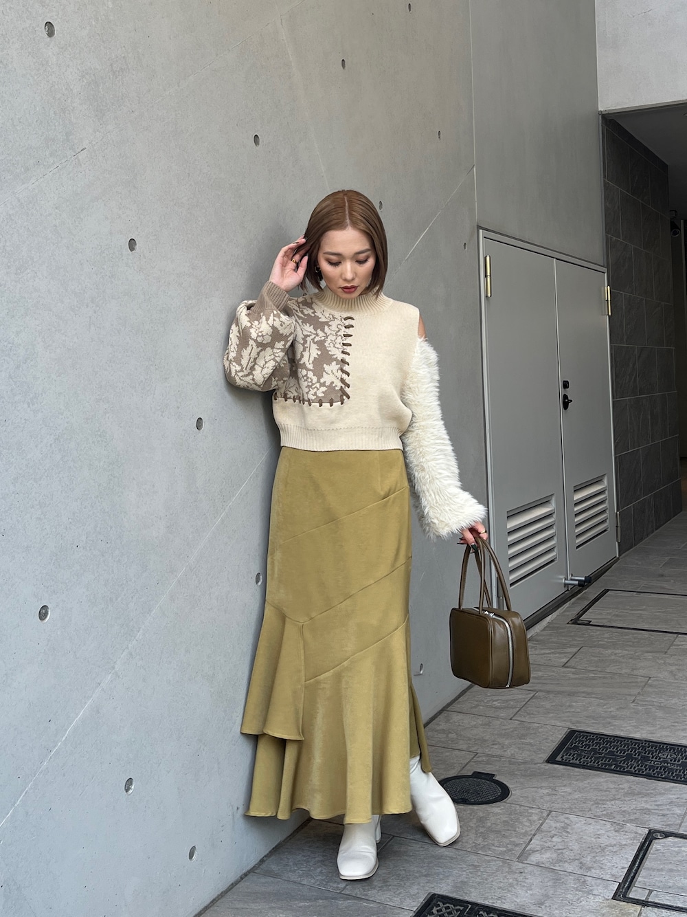 ホワイト系のニット/セーター、イエロー系のボストンバッグ、ホワイト系のブーツを着用したレディースの秋コーディネートの1枚目の写真