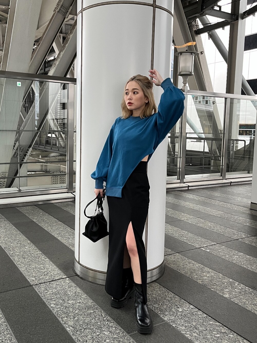 ブルー系のTシャツ/カットソー、ブラック系のスカート、ブラック系のハンドバッグを着用したレディースの冬コーディネートの1枚目の写真