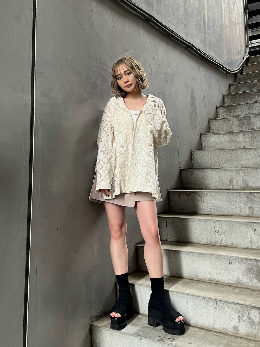 ホワイト系のテーラードジャケット、ホワイト系のキャミソール、ベージュ系のスカートを着用したレディースの春コーディネートの1枚目の写真