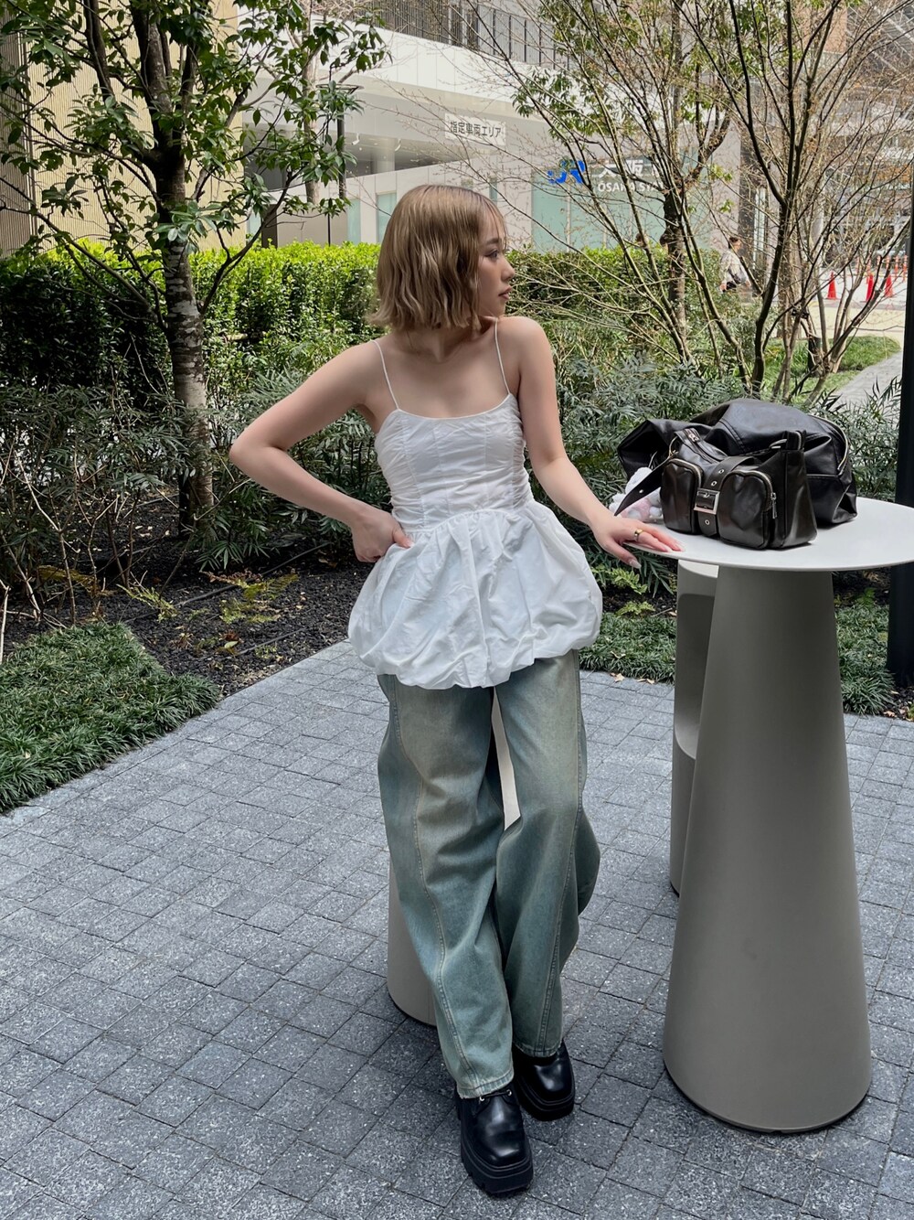 ホワイト系のキャミソール、ブルー系のデニムパンツ、ブラウン系のハンドバッグを着用したレディースの春コーディネートの1枚目の写真