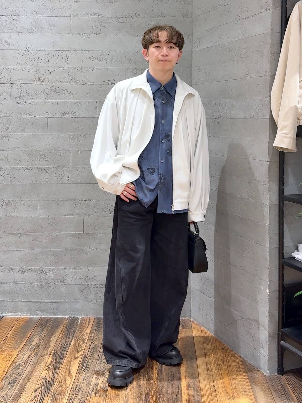 ブラック系のドレスシューズ、ブラック系のデニムパンツ、ホワイト系のブルゾンを着用したメンズの春コーディネートの1枚目の写真