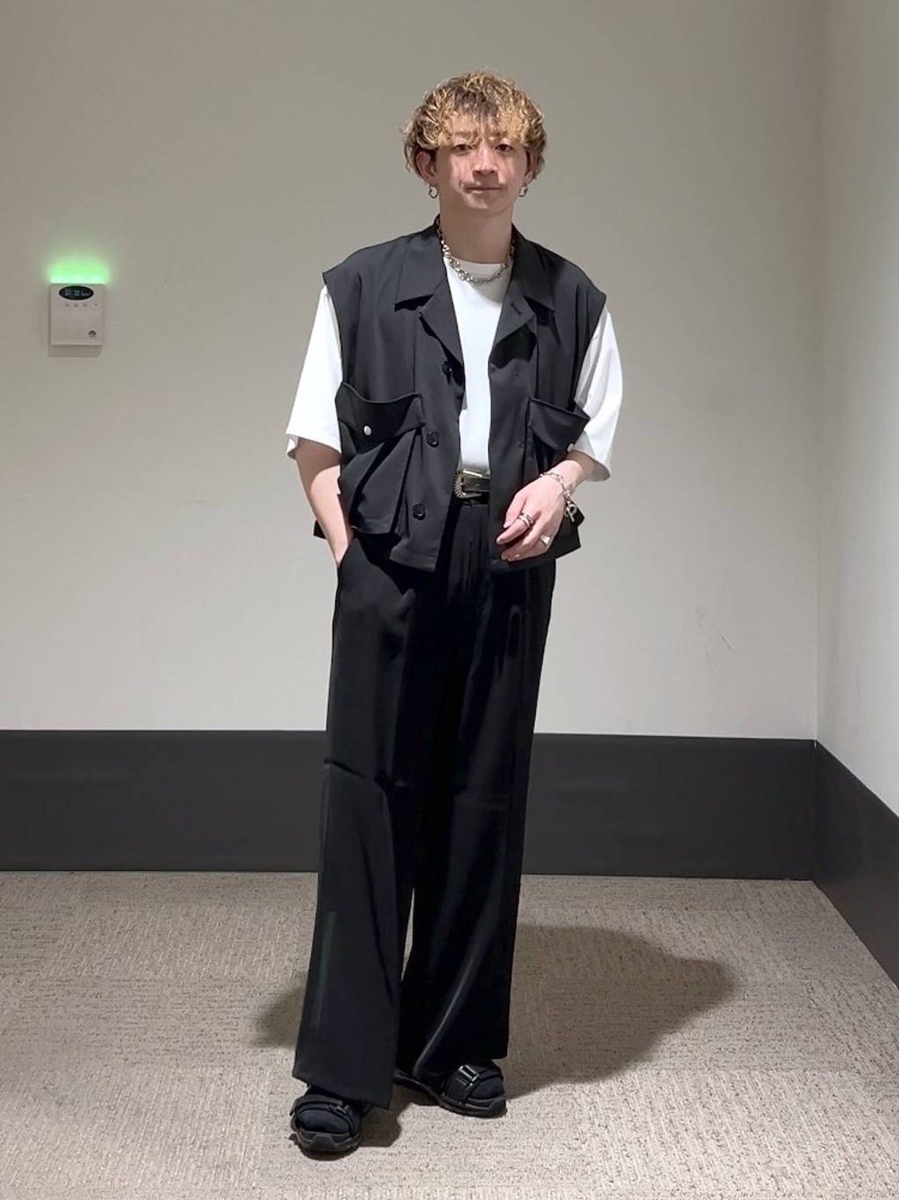 ブラック系のスラックス、ホワイト系のTシャツ/カットソー、ブラック系のサンダルを着用したメンズの夏コーディネートの1枚目の写真