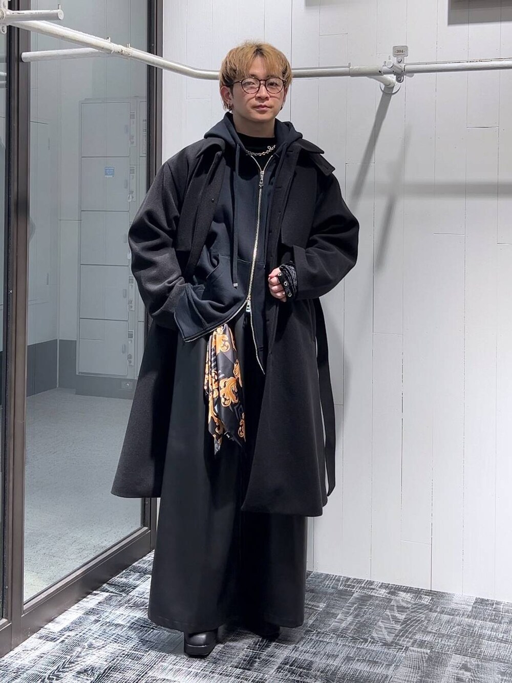 ブラック系のステンカラーコート、ブラック系のその他パンツ、ブラック系のパーカーを着用したメンズの冬コーディネートの1枚目の写真