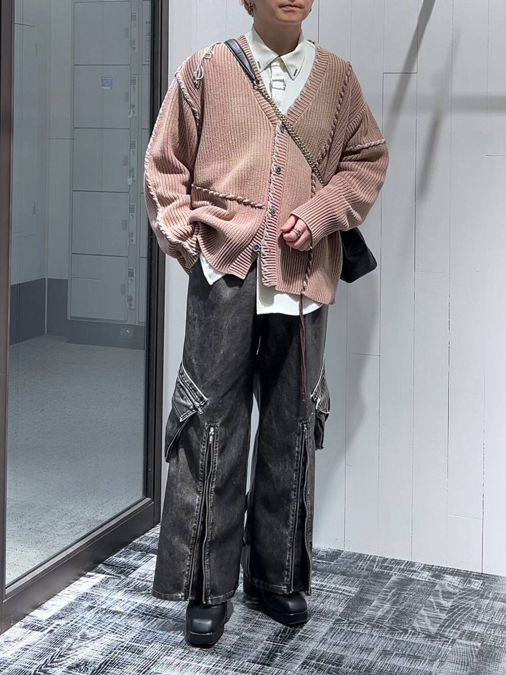 グレー系のカーゴパンツ、ブラック系のショルダーバッグ、ピンク系のカーディガン/ボレロを着用したメンズの冬コーディネートの1枚目の写真