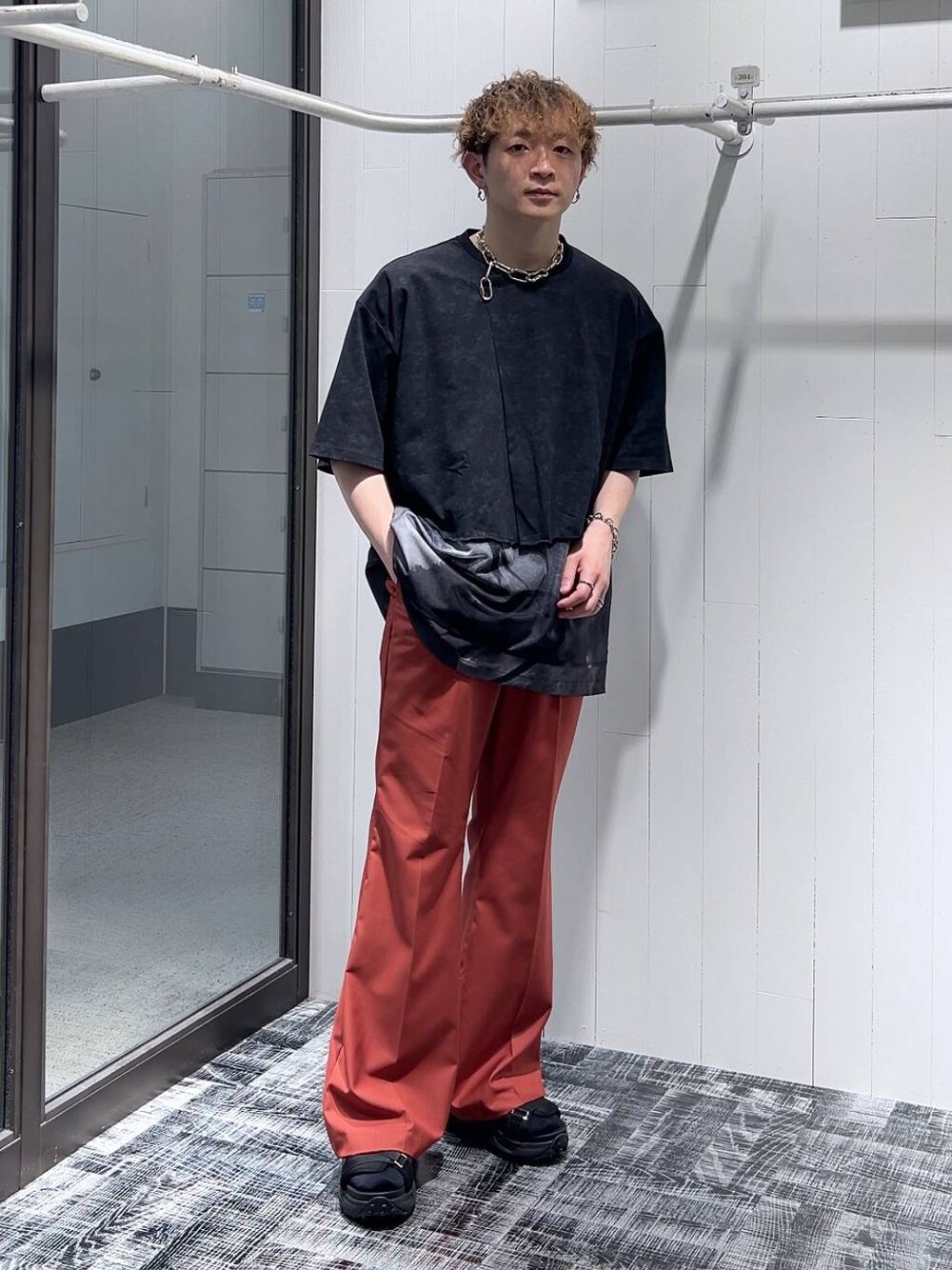 ブラック系のサンダル、オレンジ系のスラックス、ブラック系のTシャツ/カットソーを着用したメンズの夏コーディネートの1枚目の写真