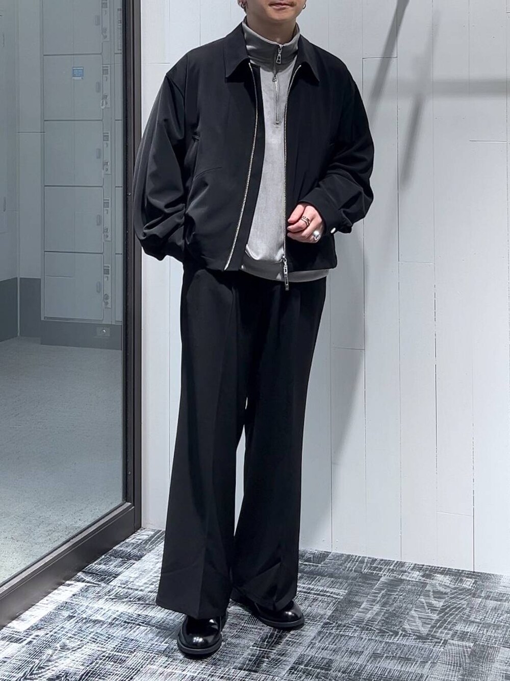 グレー系のスウェット、ブラック系のスラックス、ブラック系のドレスシューズを着用したメンズの冬コーディネートの1枚目の写真