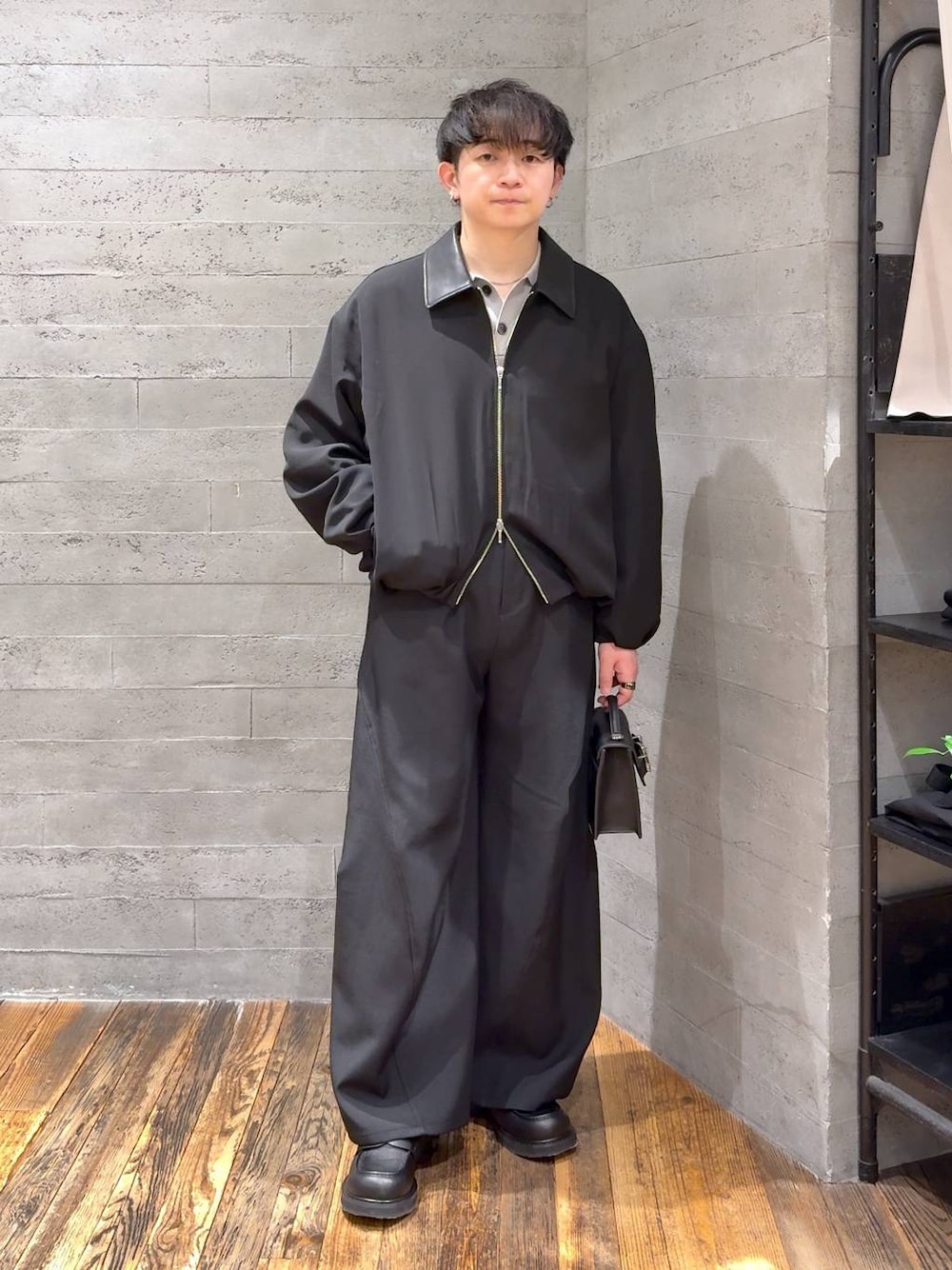 ブラック系のローファー、ブラック系のハンドバッグ、グレー系のポロシャツを着用したメンズの冬コーディネートの1枚目の写真