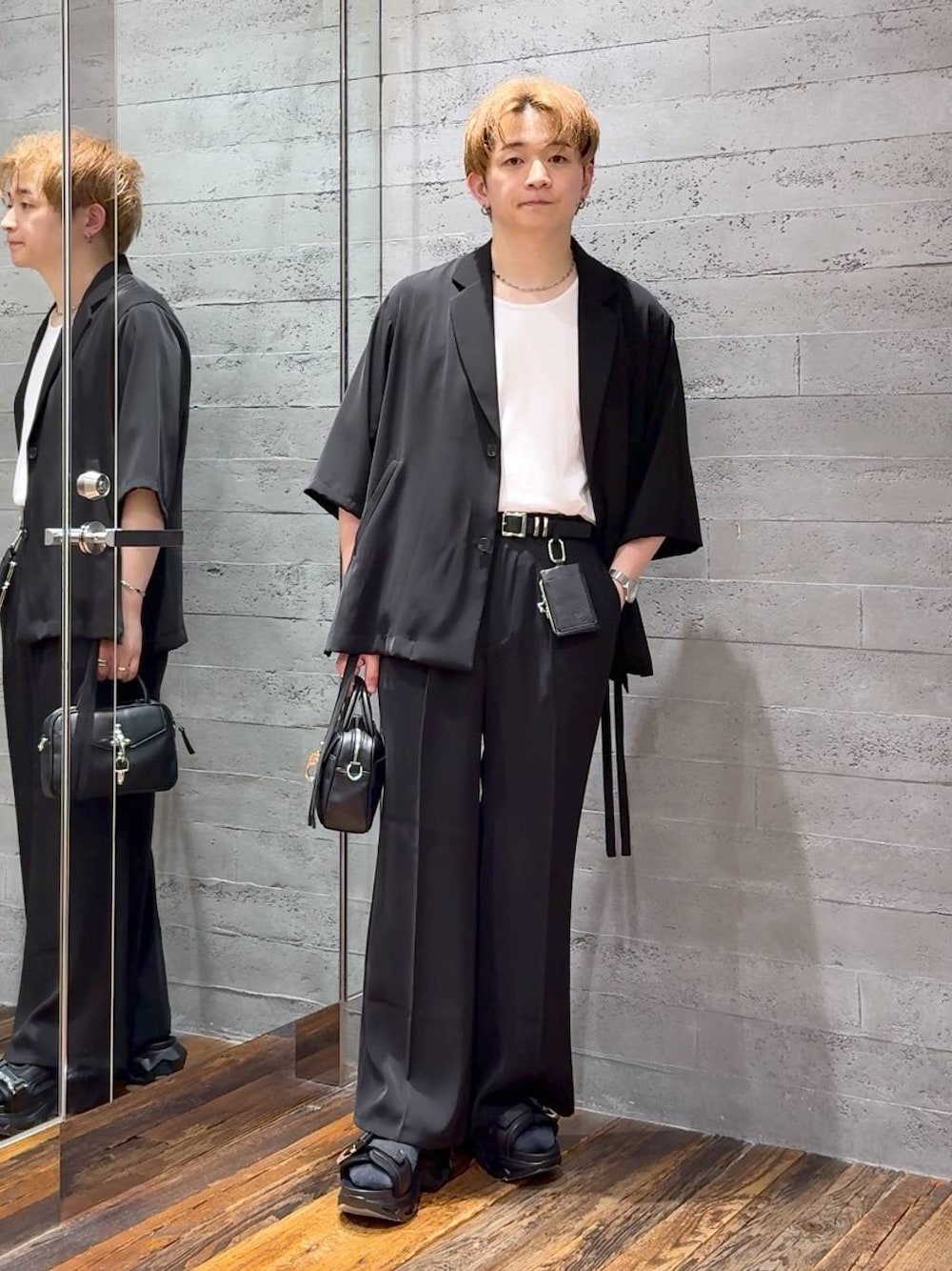 ブラック系のスラックス、ブラック系のサンダル、ホワイト系のTシャツ/カットソーを着用したメンズの夏コーディネートの1枚目の写真