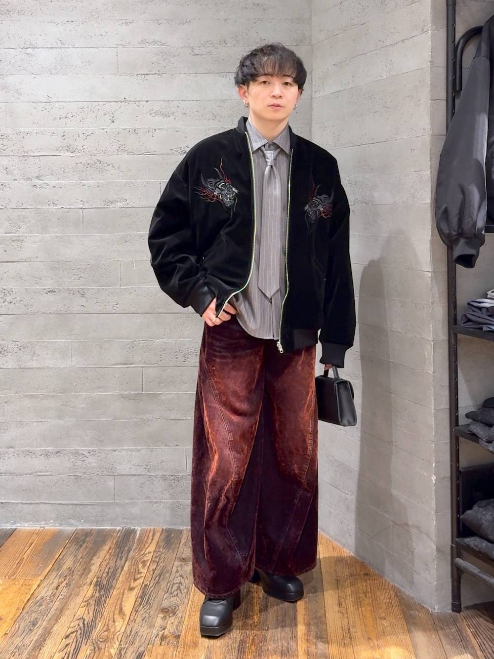 ブラック系のブーツ、レッド系のデニムパンツ、ブラック系のショルダーバッグを着用したメンズの冬コーディネートの1枚目の写真