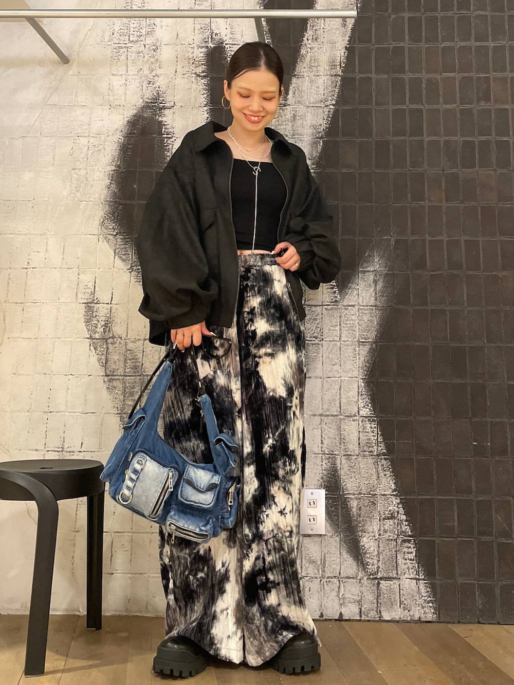 ブラック系のブルゾン、ブルー系のショルダーバッグ、ブラック系のブーツを着用したレディースの秋コーディネートの1枚目の写真