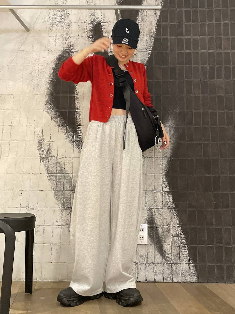 ブラック系のショルダーバッグ、ブラック系のブーツ、グレー系のスウェットパンツを着用したレディースの秋コーディネートの1枚目の写真