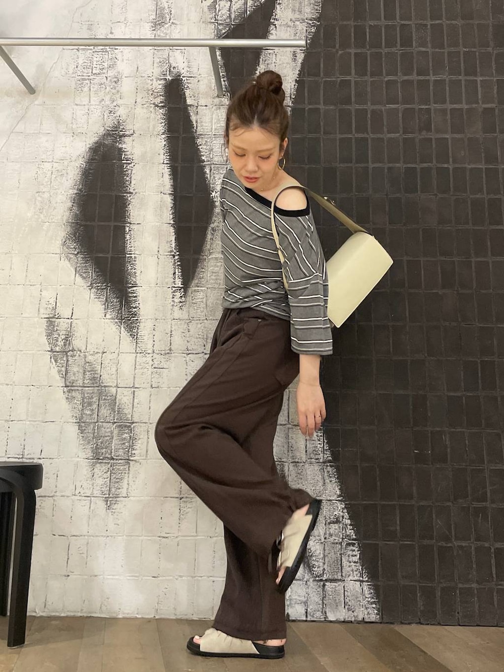 グレー系のTシャツ/カットソー、ブラウン系のデニムパンツ、ホワイト系のサンダルを着用したレディースの夏コーディネートの1枚目の写真