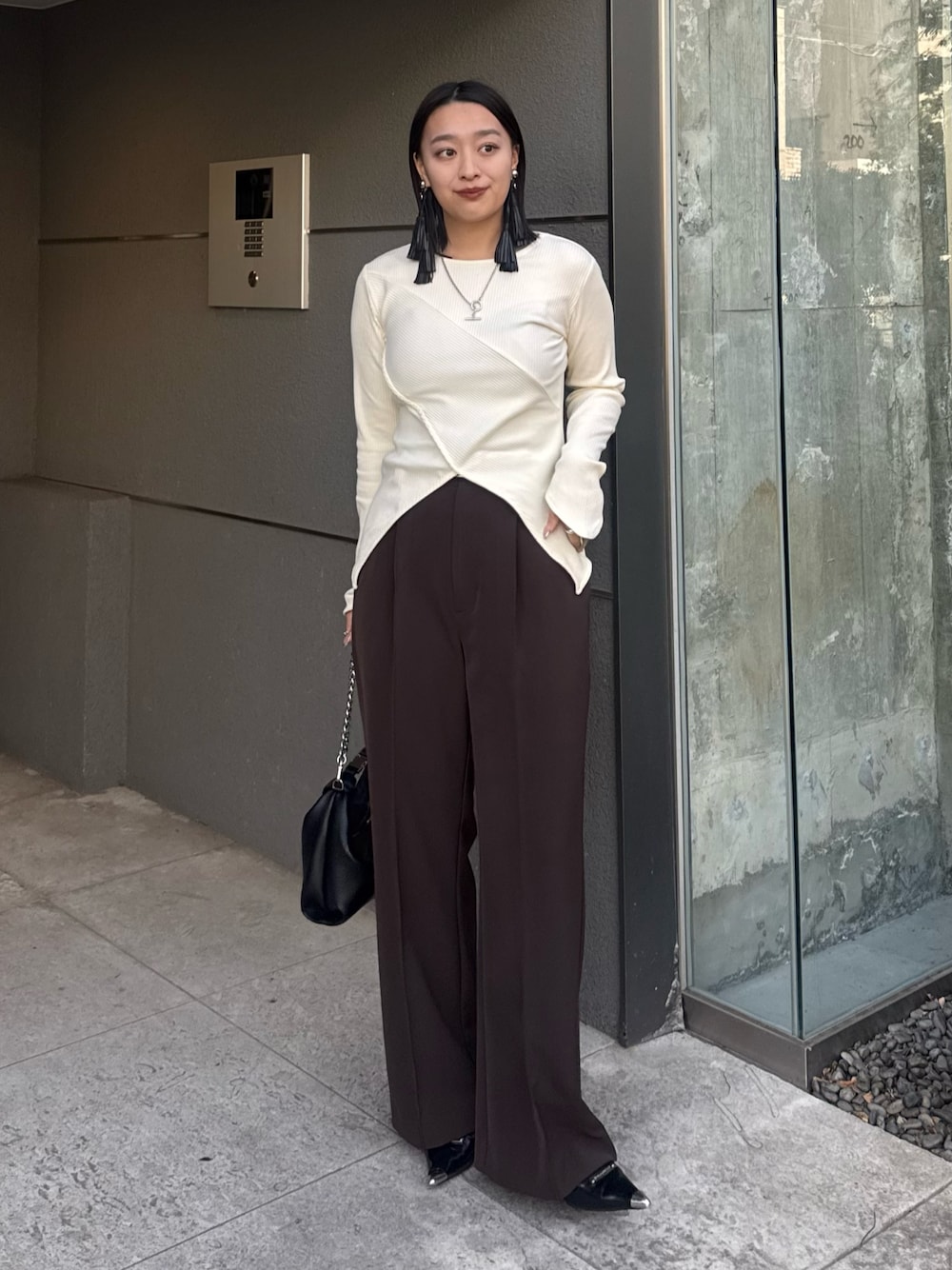 ホワイト系のTシャツ/カットソー、ブラウン系のスラックス、ブラック系のトートバッグを着用したレディースの冬コーディネートの1枚目の写真