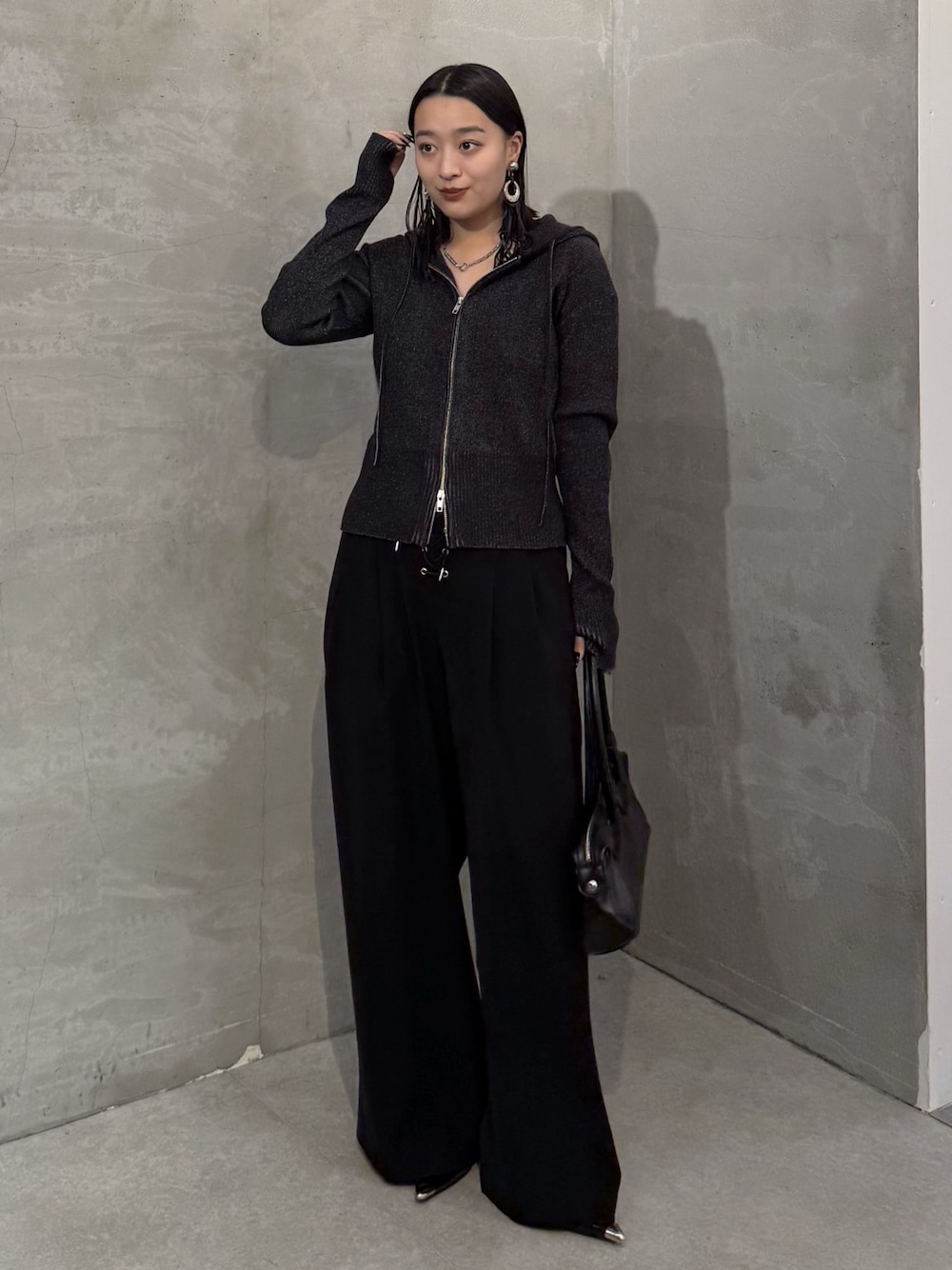 ブラック系のニット/セーター、ブラック系のスラックス、ブラック系のトートバッグを着用したレディースの冬コーディネートの1枚目の写真