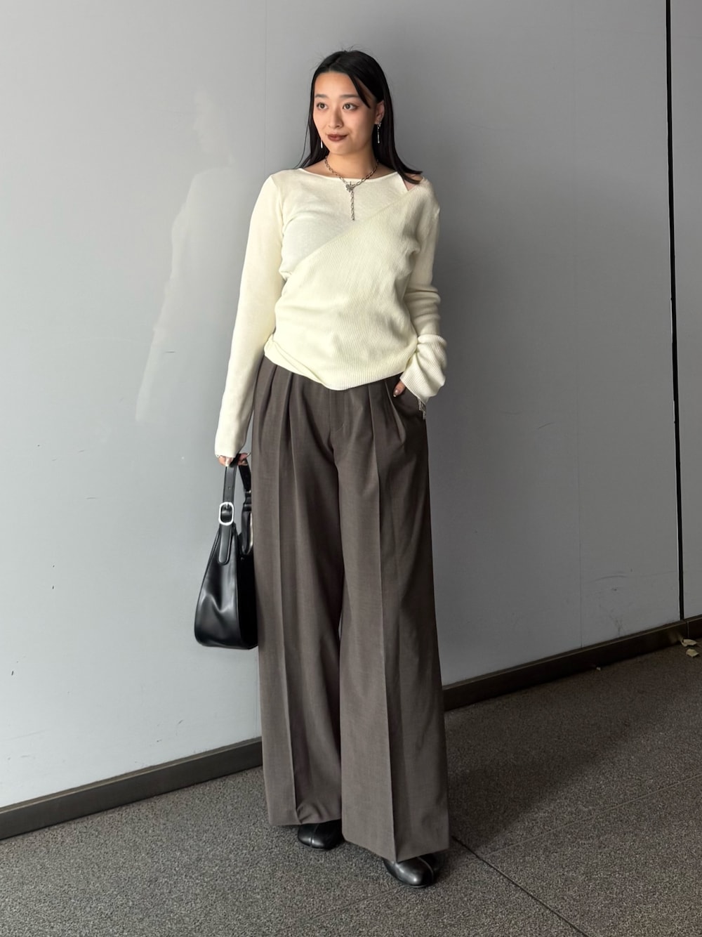 ホワイト系のニット/セーター、ブラウン系のスラックス、ブラック系のブーツを着用したレディースの夏コーディネートの1枚目の写真