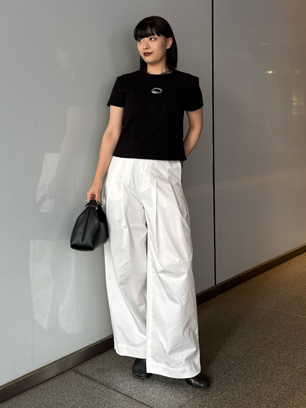 ブラック系のTシャツ/カットソー、ホワイト系のスラックス、ブラック系のショルダーバッグを着用したレディースの春コーディネートの1枚目の写真