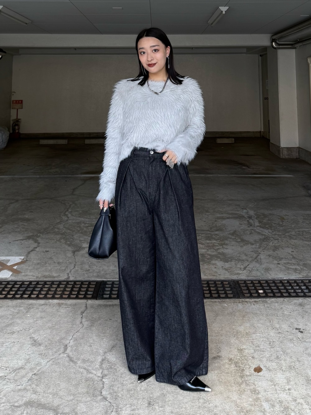 ブラック系のデニムパンツ、ブラック系のトートバッグ、グレー系のニット/セーターを着用したレディースの秋コーディネートの1枚目の写真