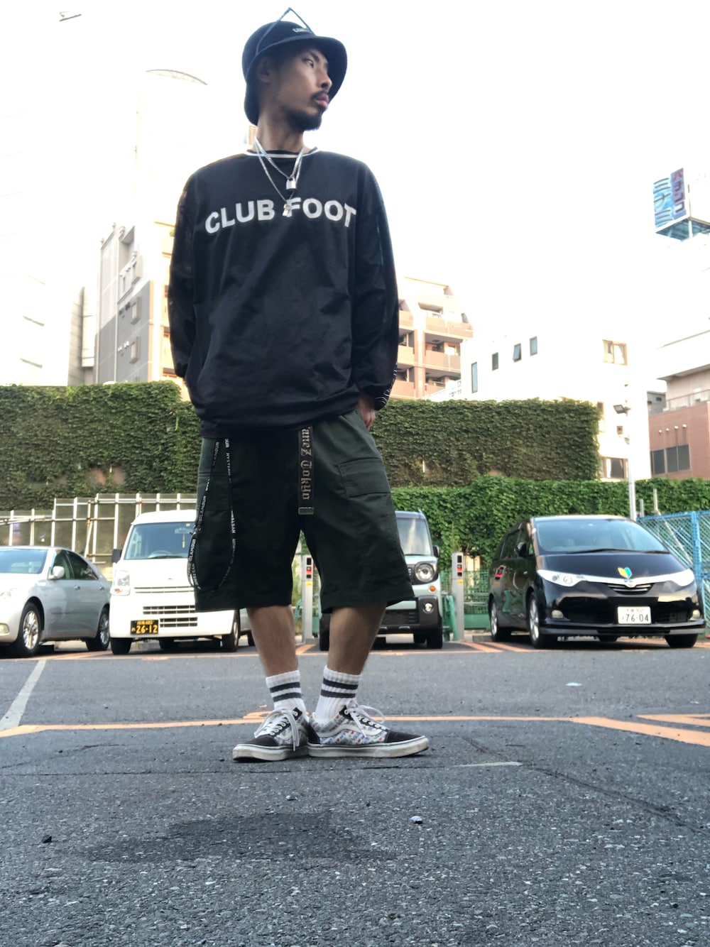 グリーン系のカーゴパンツ、ブラック系のスニーカー、ブラック系のハットを着用したメンズの夏コーディネートの1枚目の写真