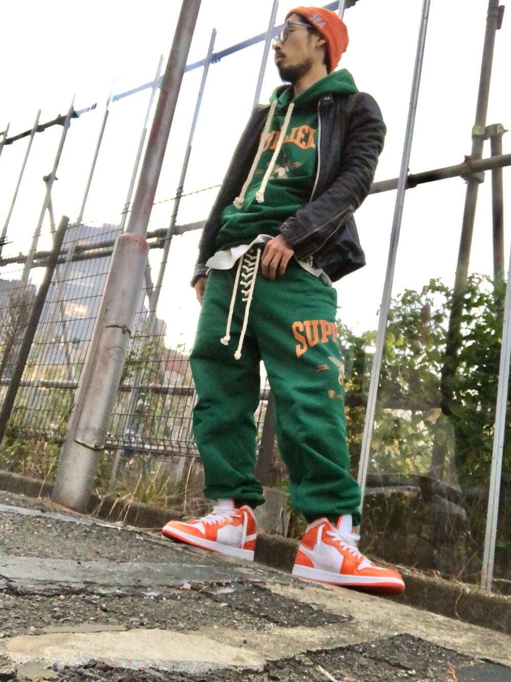 グリーン系のスウェットパンツ、ブラック系のライダースジャケット、オレンジ系のスニーカーを着用したメンズの秋コーディネートの1枚目の写真