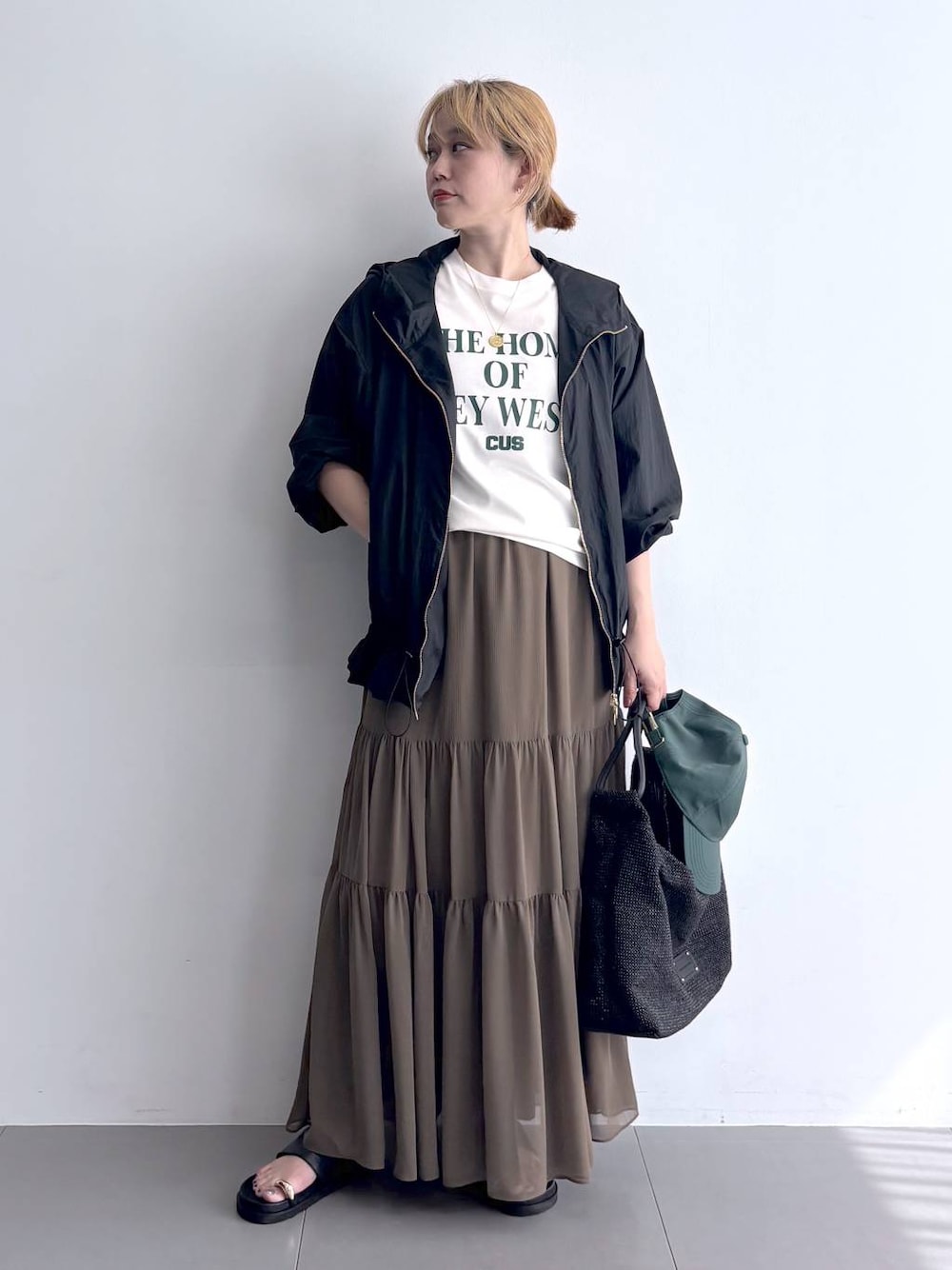 ホワイト系のTシャツ/カットソー、ブラック系のブルゾン、グリーン系のスカートを着用したレディースの春コーディネートの1枚目の写真