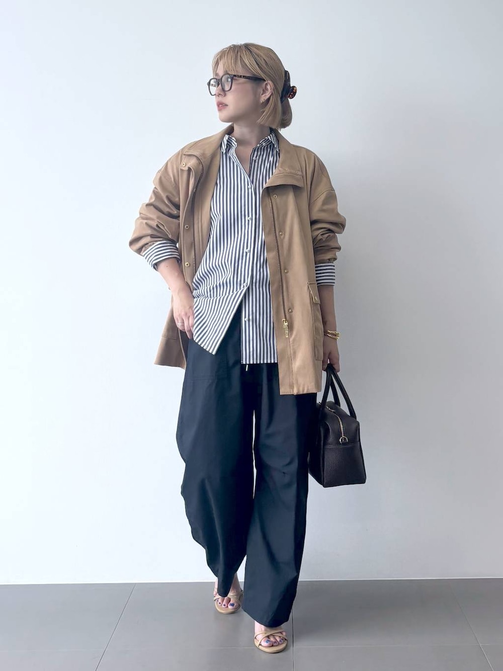 ブラウン系のボストンバッグ、ホワイト系のシャツ/ブラウス、ベージュ系のサンダルを着用したレディースの秋コーディネートの1枚目の写真
