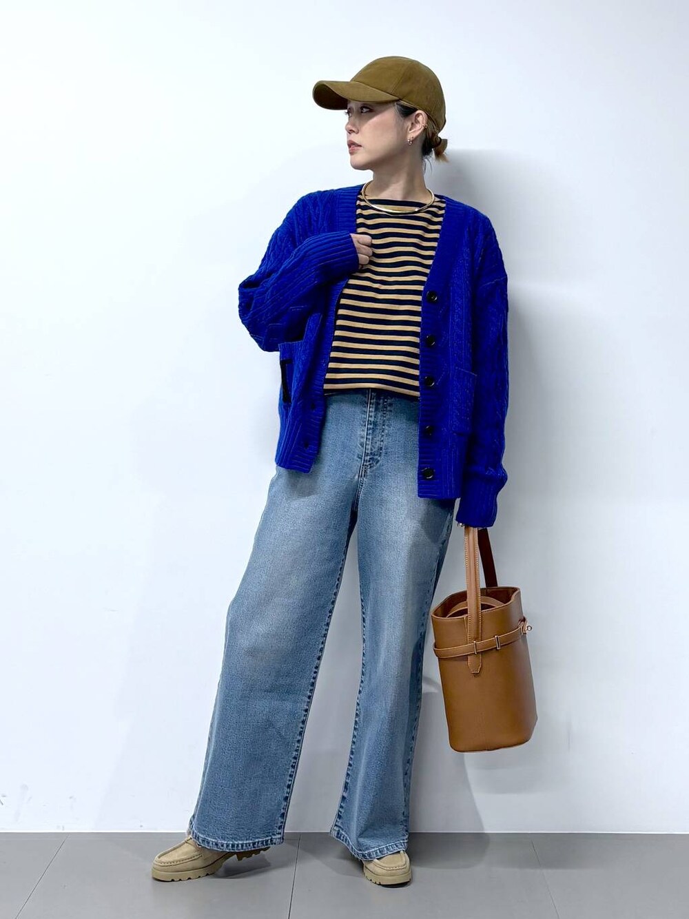 ブルー系のデニムパンツ、ベージュ系のTシャツ/カットソー、イエロー系のハンドバッグを着用したレディースの秋コーディネートの1枚目の写真