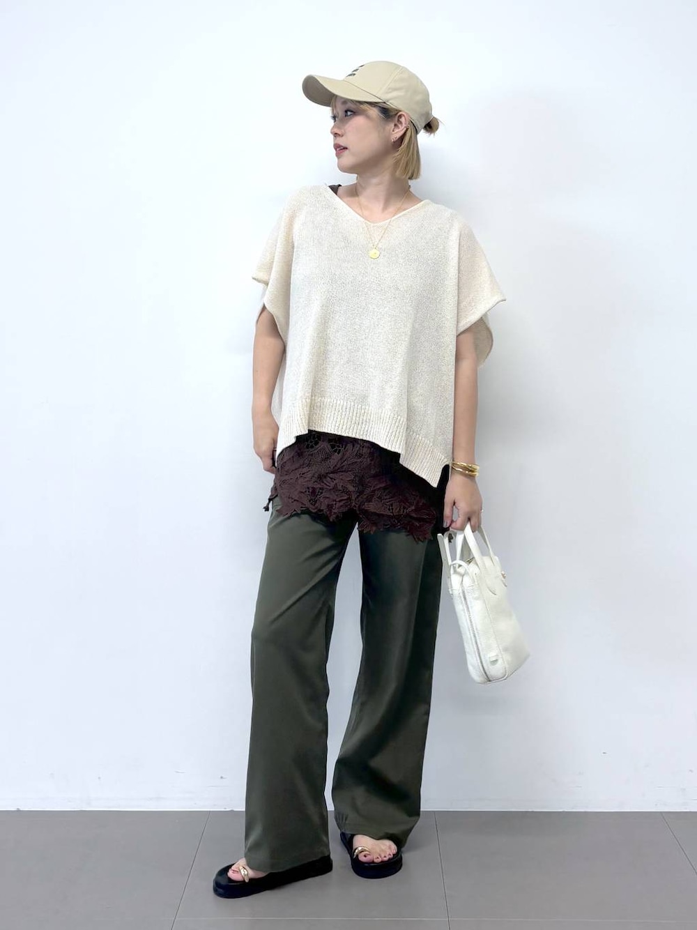 グリーン系のチノパンツ、ホワイト系のショルダーバッグ、ブラック系のサンダルを着用したレディースの夏コーディネートの1枚目の写真
