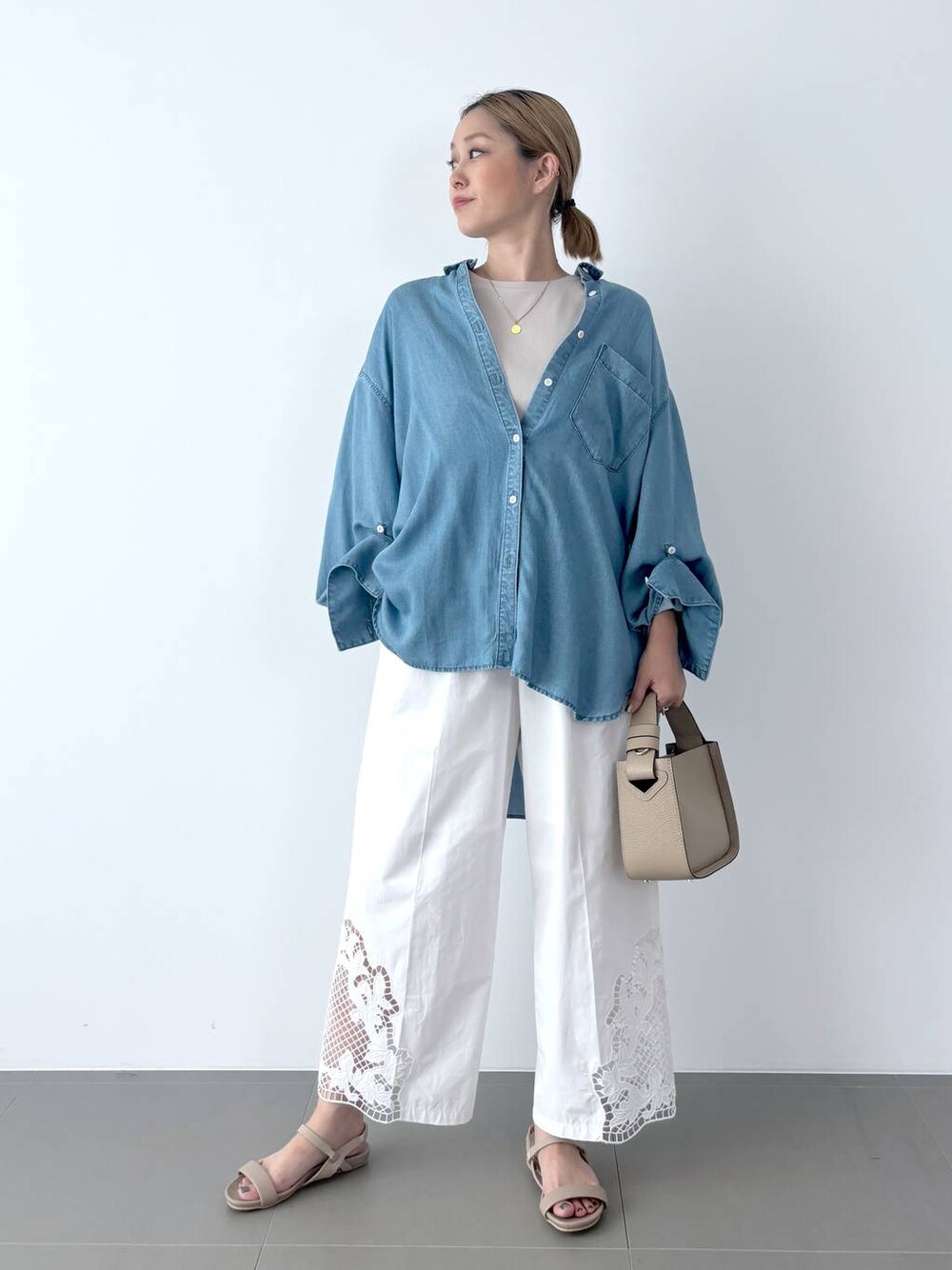 ブラウン系のハンドバッグ、ベージュ系のサンダル、ブルー系のシャツ/ブラウスを着用したレディースの夏コーディネートの1枚目の写真