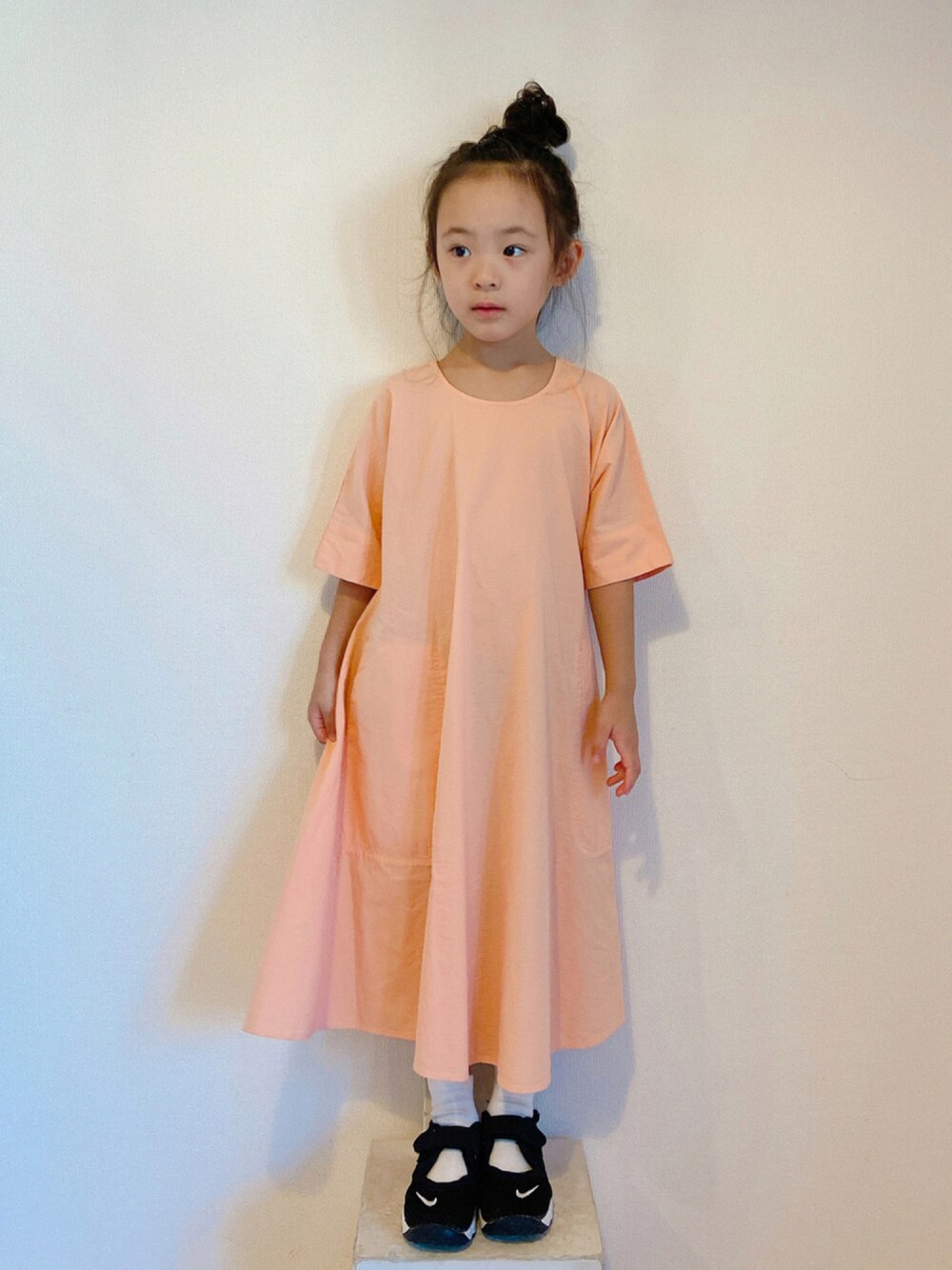 ブラック系のスニーカー、オレンジ系のワンピース/ドレスを着用したキッズの夏コーディネートの1枚目の写真