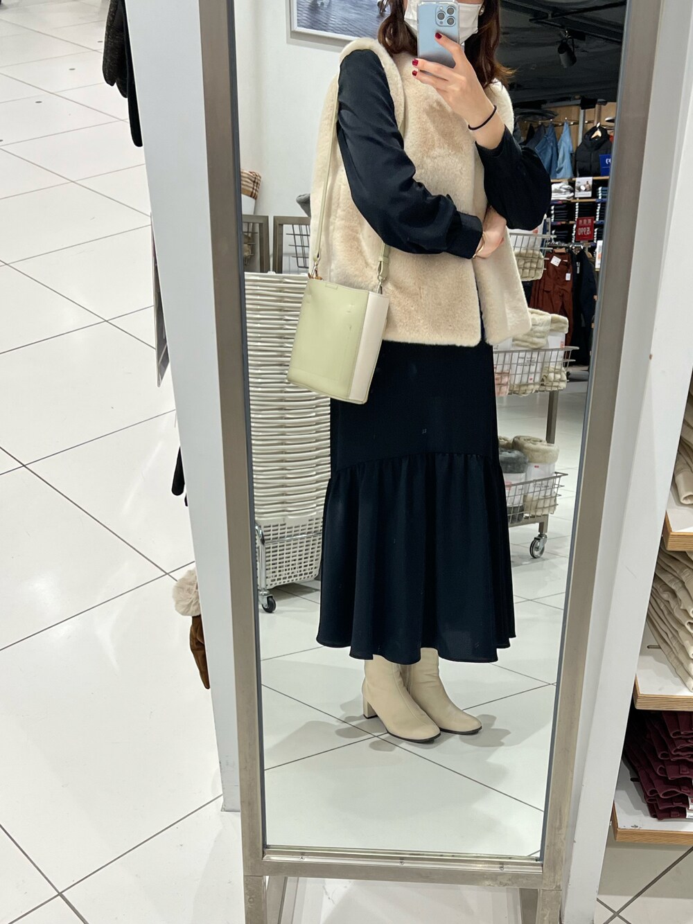 ブラック系のワンピース、ホワイト系のブーツを着用したレディースの冬コーディネートの1枚目の写真