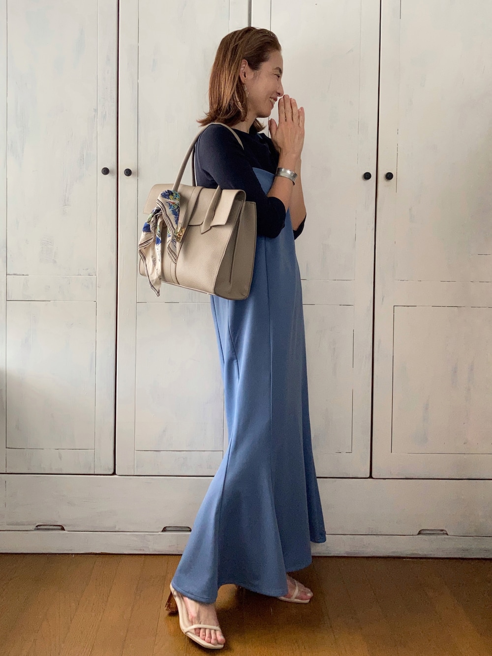 ブルー系のワンピース、ベージュ系のビジネスバッグ、ベージュ系のサンダルを着用したレディースの夏コーディネートの1枚目の写真