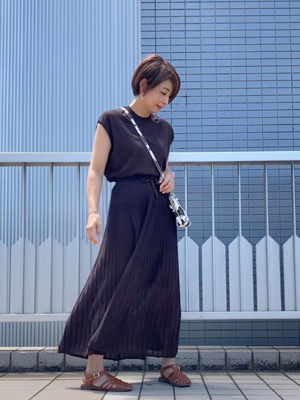 ブラウン系のニット/セーター、ブラウン系のスカート、その他のショルダーバッグを着用したレディースの夏コーディネートの1枚目の写真