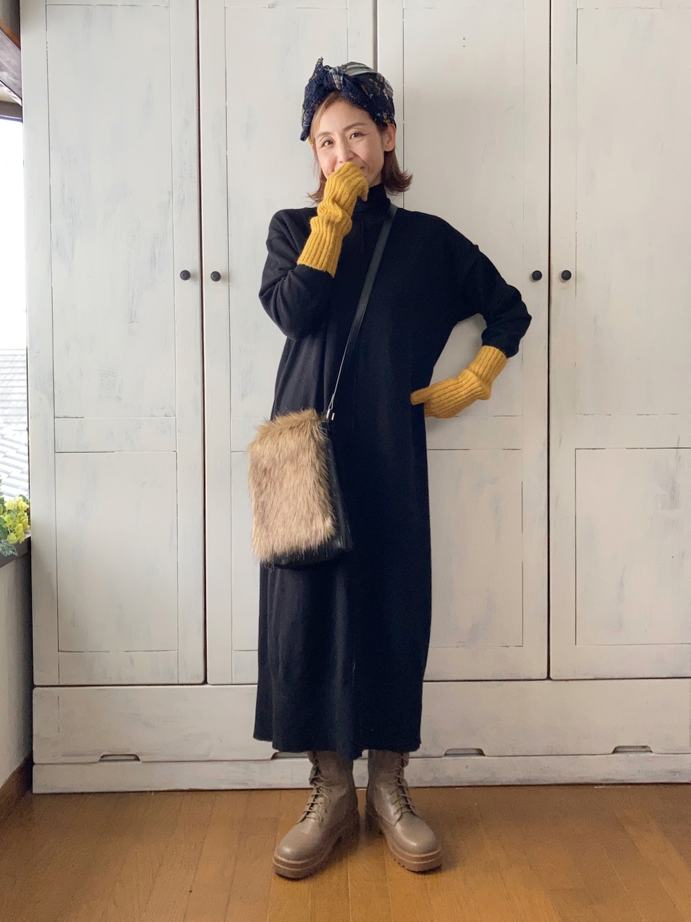 ブラック系のワンピース、ブラウン系のショルダーバッグ、ブラウン系のブーツを着用したレディースの秋コーディネートの1枚目の写真