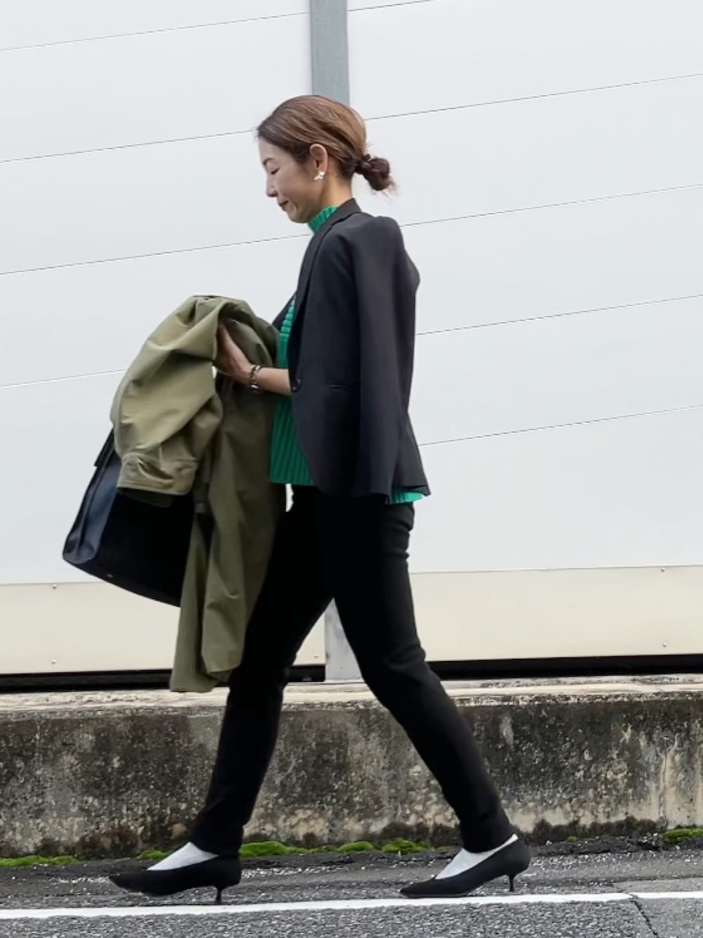 ブラック系のパンツ、ブラック系のスーツセット、グリーン系のステンカラーコートを着用したレディースの冬コーディネートの1枚目の写真