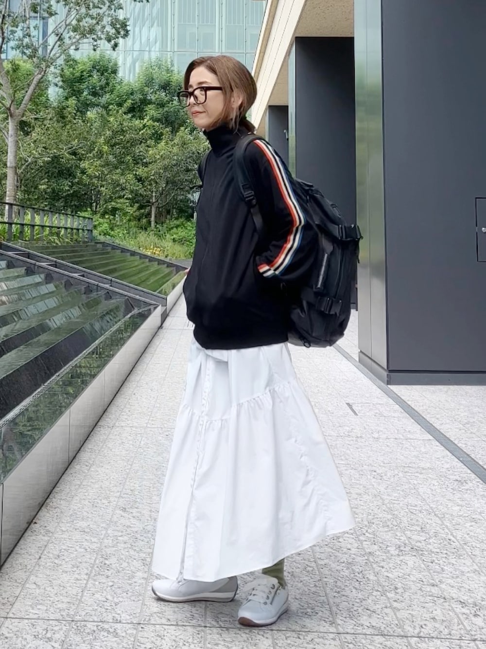 ブラック系のジャージ、ブラック系のバックパック/リュック、ホワイト系のスニーカーを着用したレディースの秋コーディネートの1枚目の写真