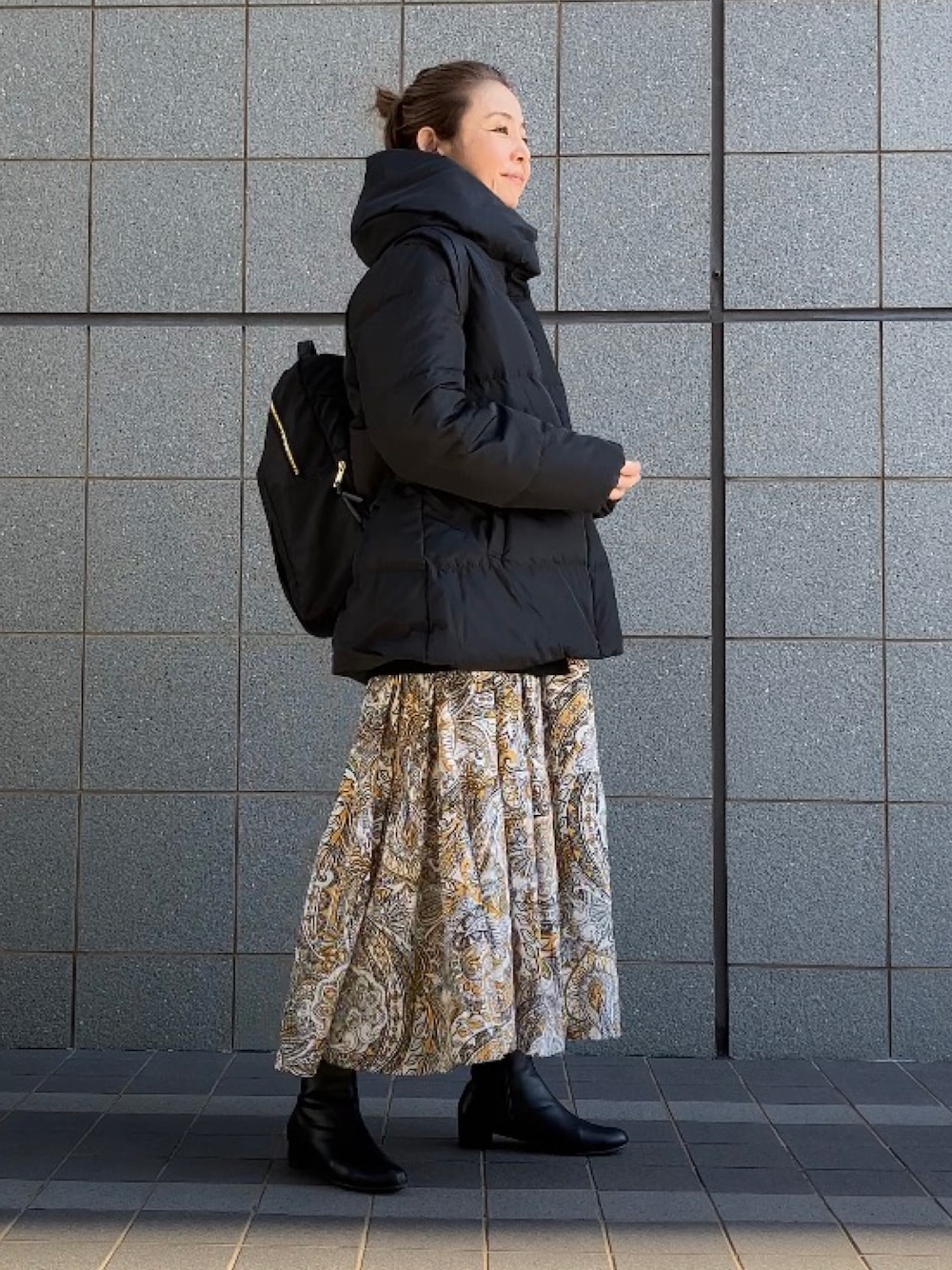 ブラック系のダウンジャケット/コート、イエロー系のワンピース、ブラック系のブーツを着用したレディースの冬コーディネートの1枚目の写真