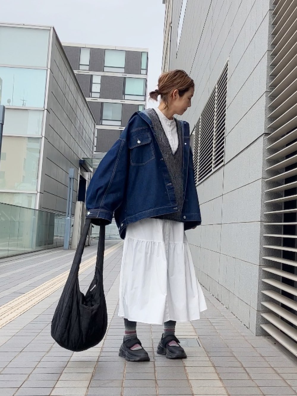 グレー系のベスト、ブルー系のデニムジャケット、ホワイト系のワンピース/ドレスを着用したレディースの春コーディネートの1枚目の写真