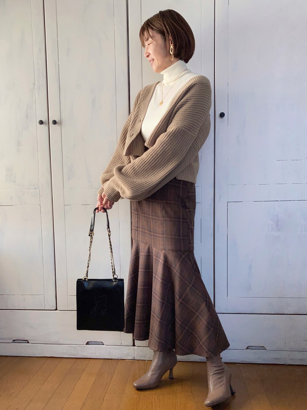ブラウン系のスカート、ベージュ系のカーディガン/ボレロ、グレー系のブーツを着用したレディースの秋コーディネートの1枚目の写真