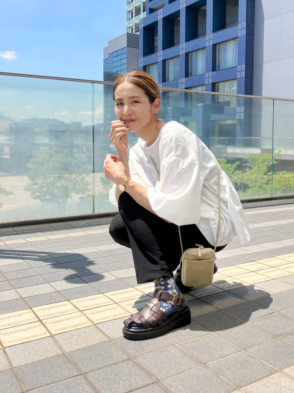 ホワイト系のシャツ/ブラウス、ブラック系のパンツ、ゴールド系のバッグを着用したレディースの夏コーディネートの1枚目の写真