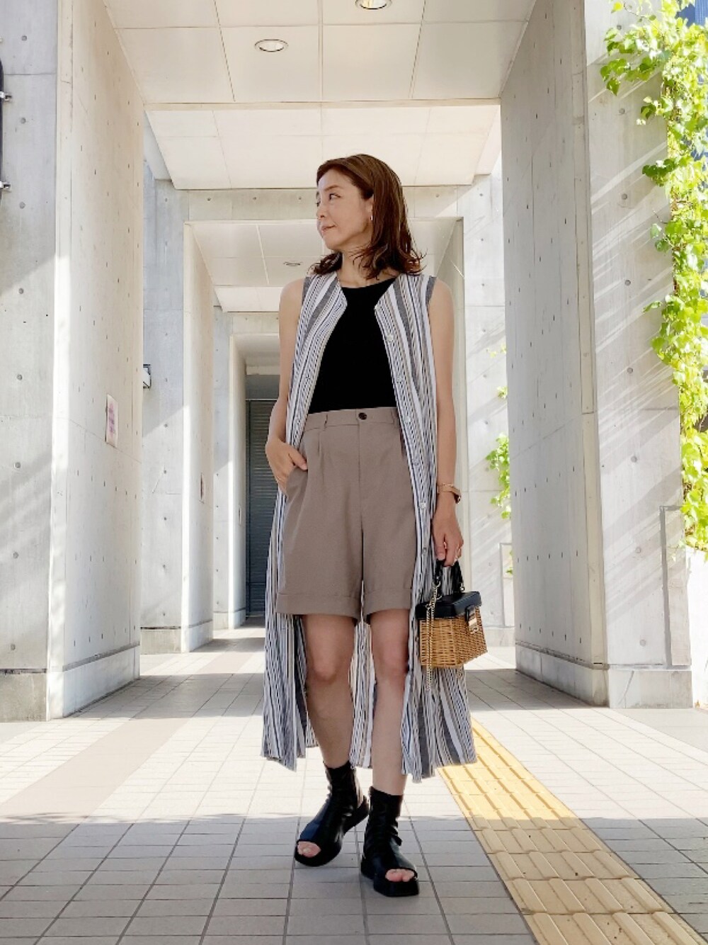 ベージュ系のパンツ、ホワイト系のワンピース、ブラック系のブーツを着用したレディースの夏コーディネートの1枚目の写真