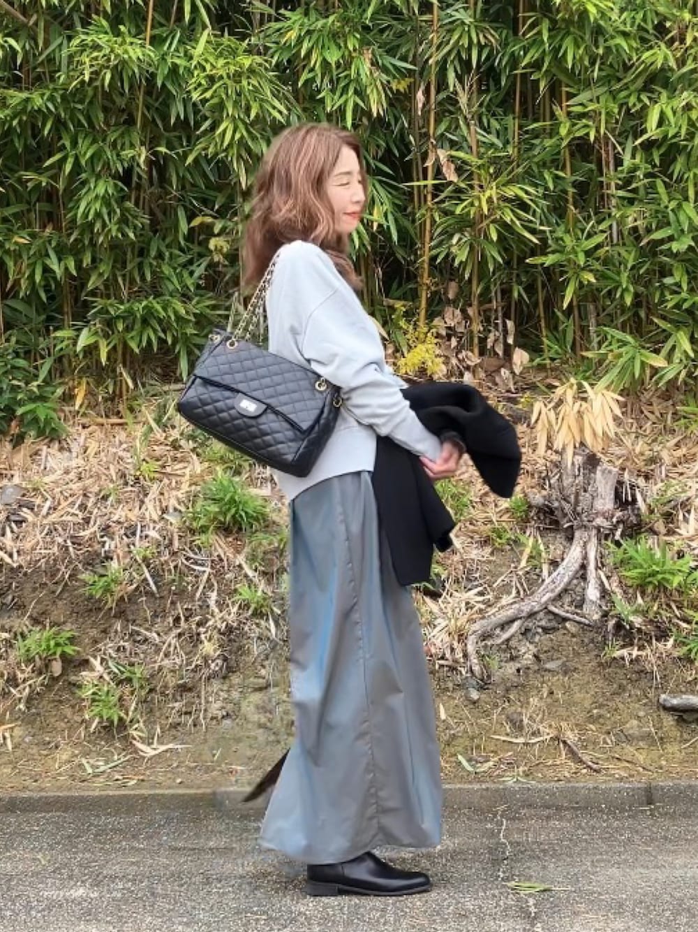 ブラック系のボストンバッグ、グレー系のスウェット、グリーン系のスカートを着用したレディースの冬コーディネートの1枚目の写真