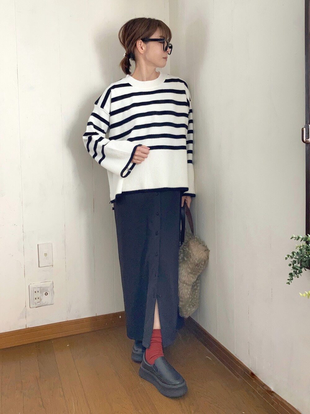 ブラック系のジャンパースカート、ホワイト系のニット/セーター、ブラック系のスリッポンを着用したレディースの冬コーディネートの1枚目の写真