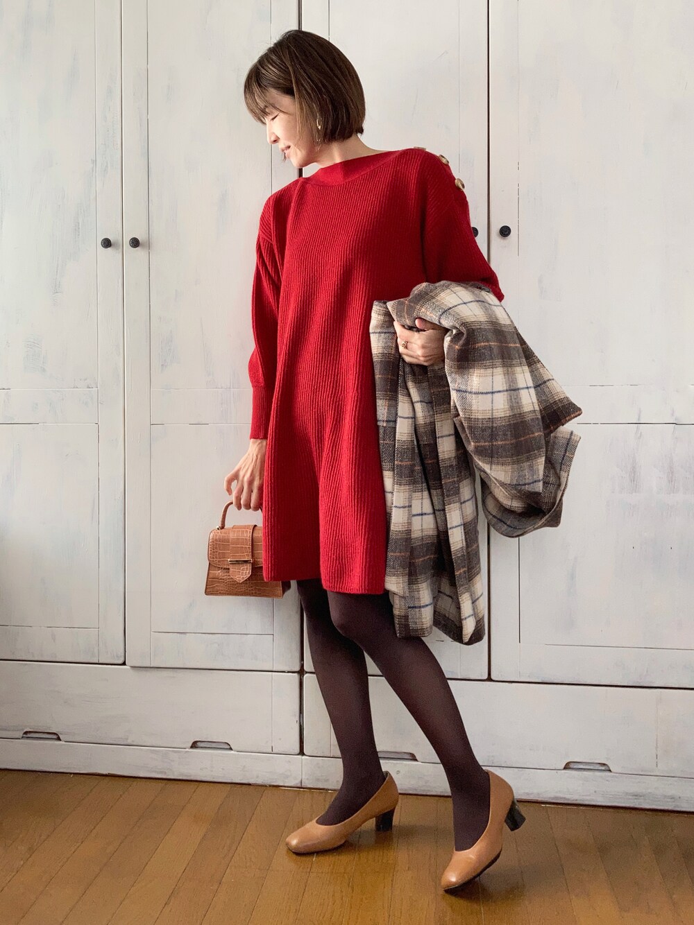 レッド系のワンピース、ブラウン系のチェスターコート、ベージュ系のパンプスを着用したレディースの冬コーディネートの1枚目の写真