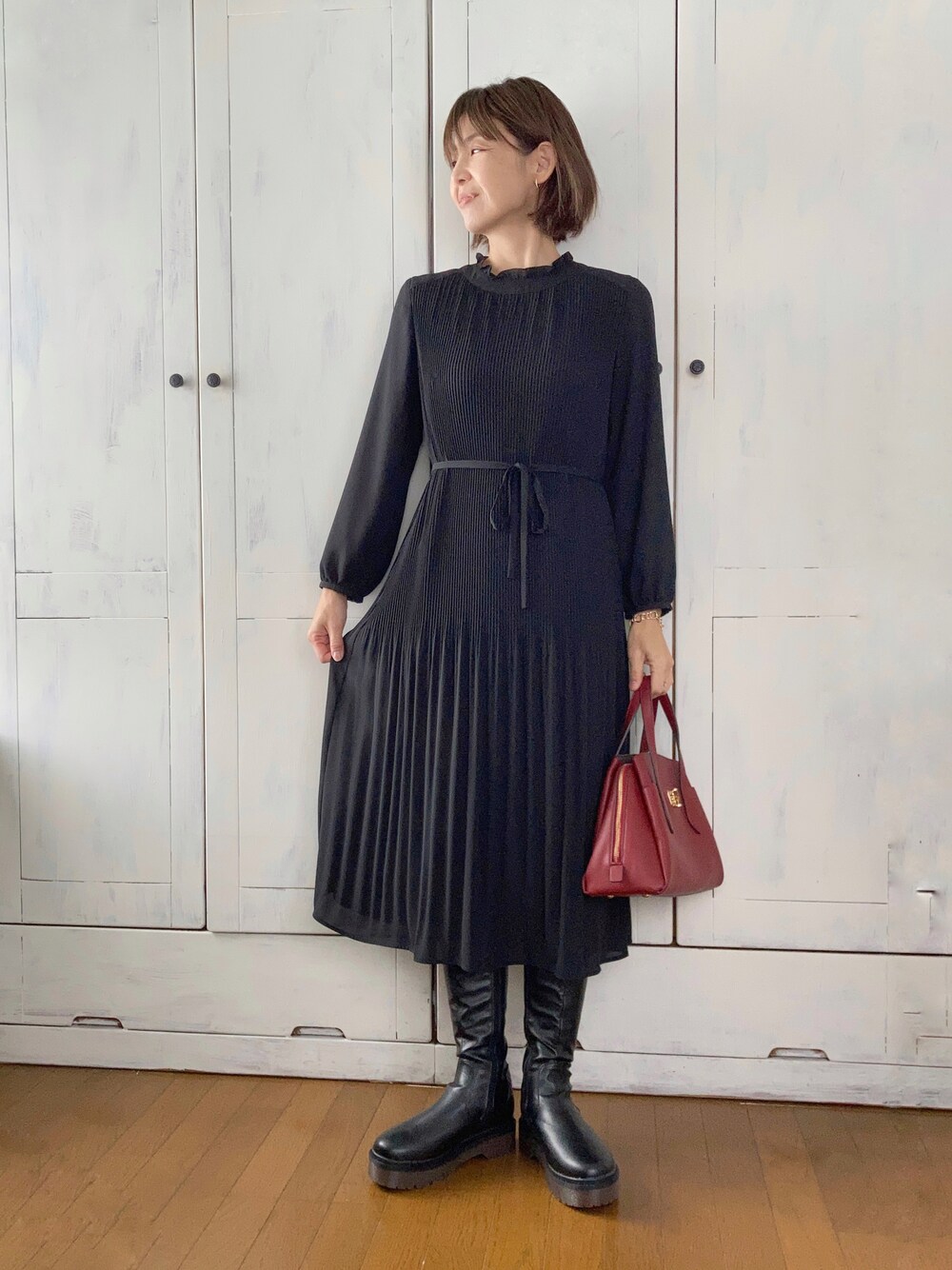 ブラック系のワンピース、ブラック系のハンドバッグ、ブラック系のブーツを着用したレディースの冬コーディネートの1枚目の写真