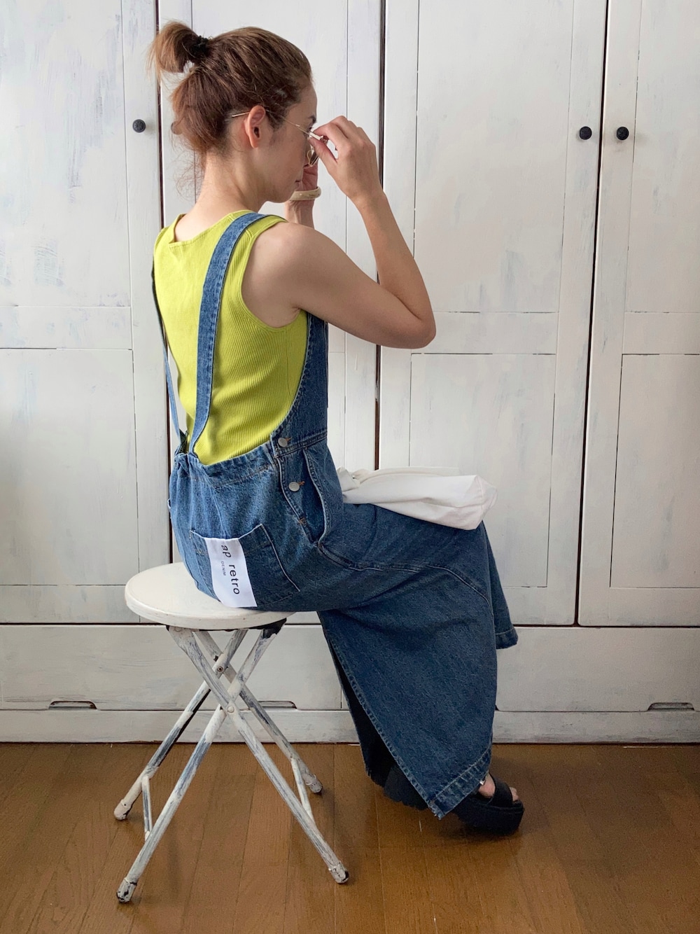 ブルー系のサロペット/オーバーオール、グリーン系のタンクトップ、ホワイト系のトートバッグを着用したレディースの夏コーディネートの1枚目の写真