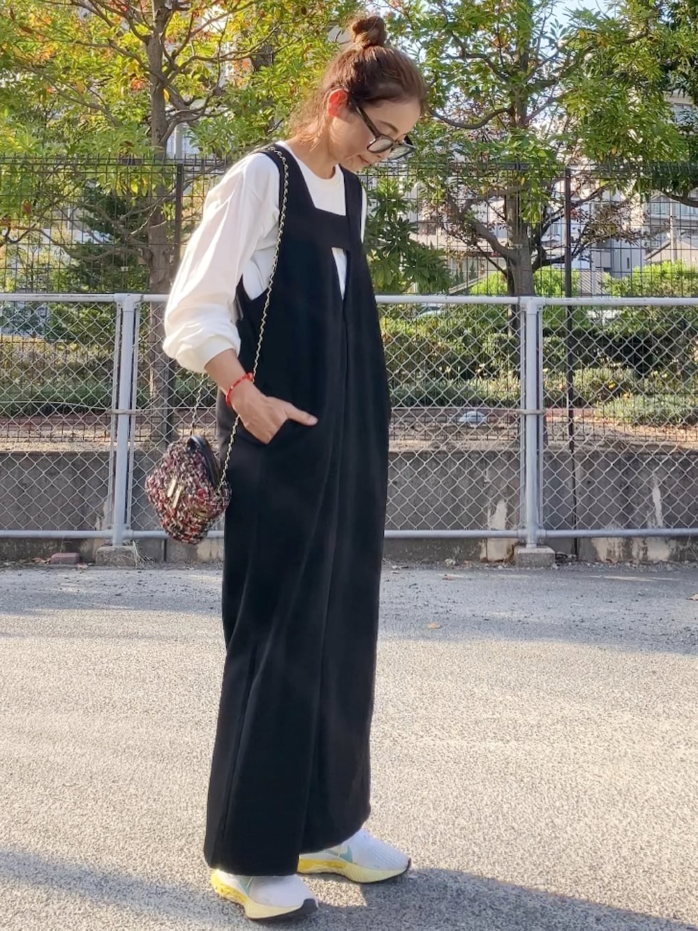 ブラック系のジャンパースカート、その他のハンドバッグ、ホワイト系のスニーカーを着用したレディースの秋コーディネートの1枚目の写真