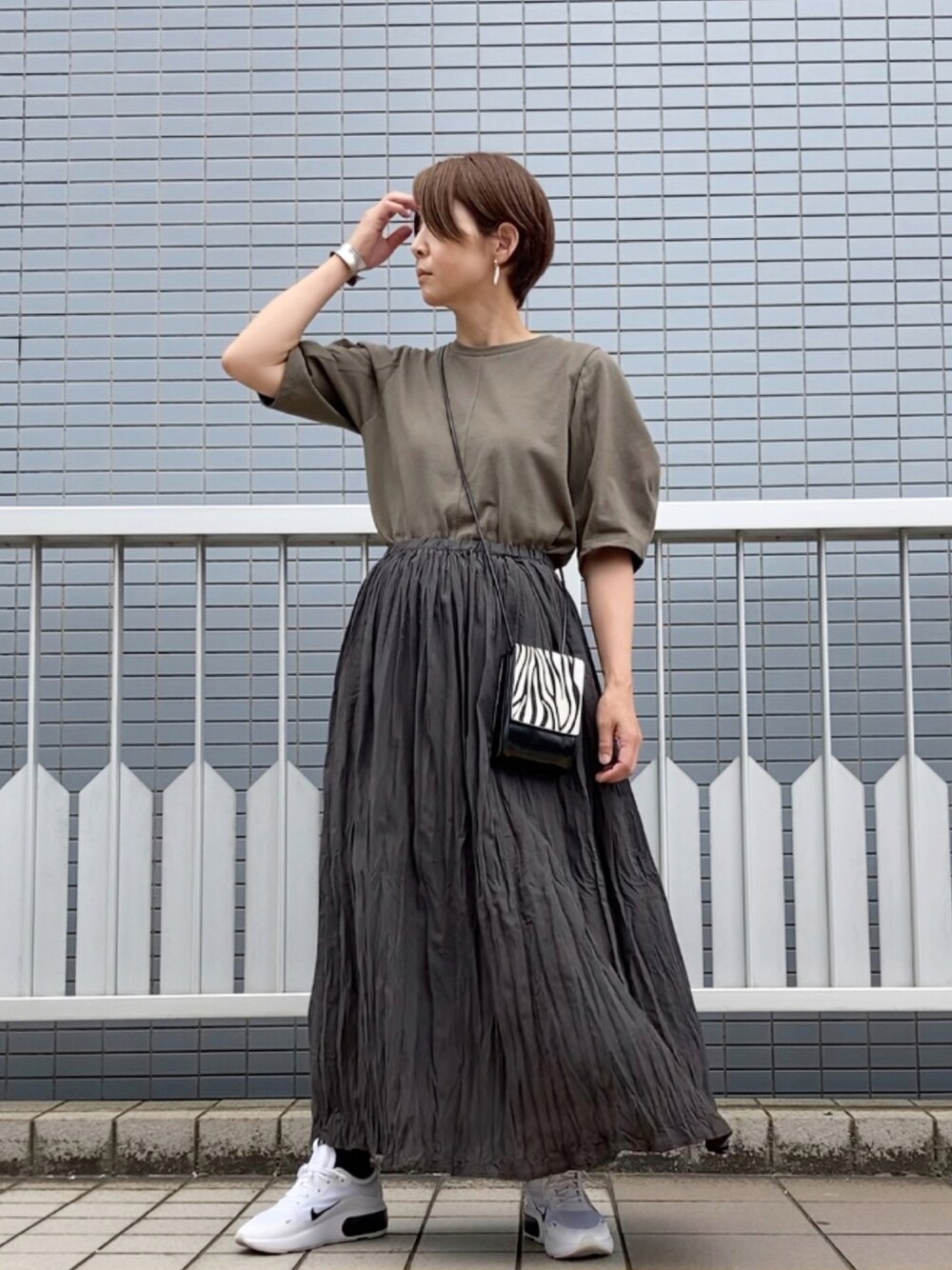 グリーン系のTシャツ/カットソー、グレー系のスカート、ブラック系のショルダーバッグを着用したレディースの夏コーディネートの1枚目の写真