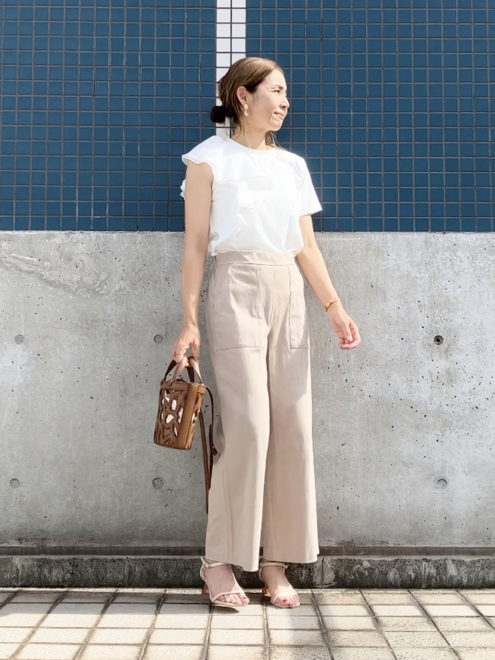 ホワイト系のTシャツ/カットソー、ベージュ系のパンツ、ブラウン系のバッグを着用したレディースの夏コーディネートの1枚目の写真